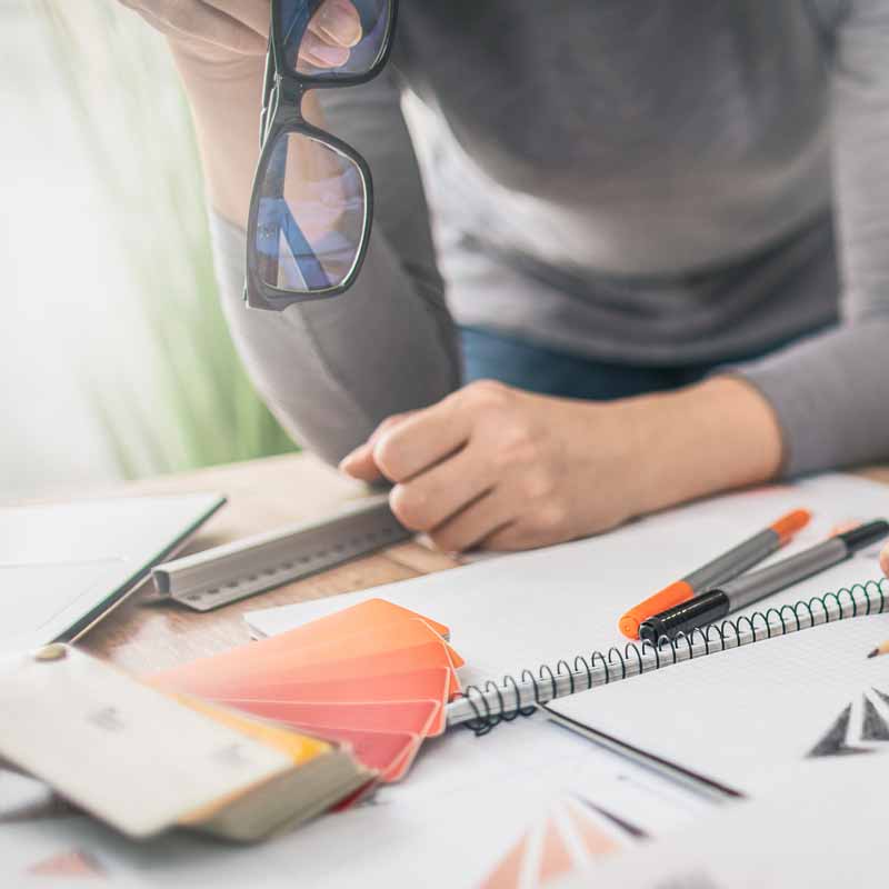 A photo of a person looking at color swatches and notepads for Brand Strategy on a desk.